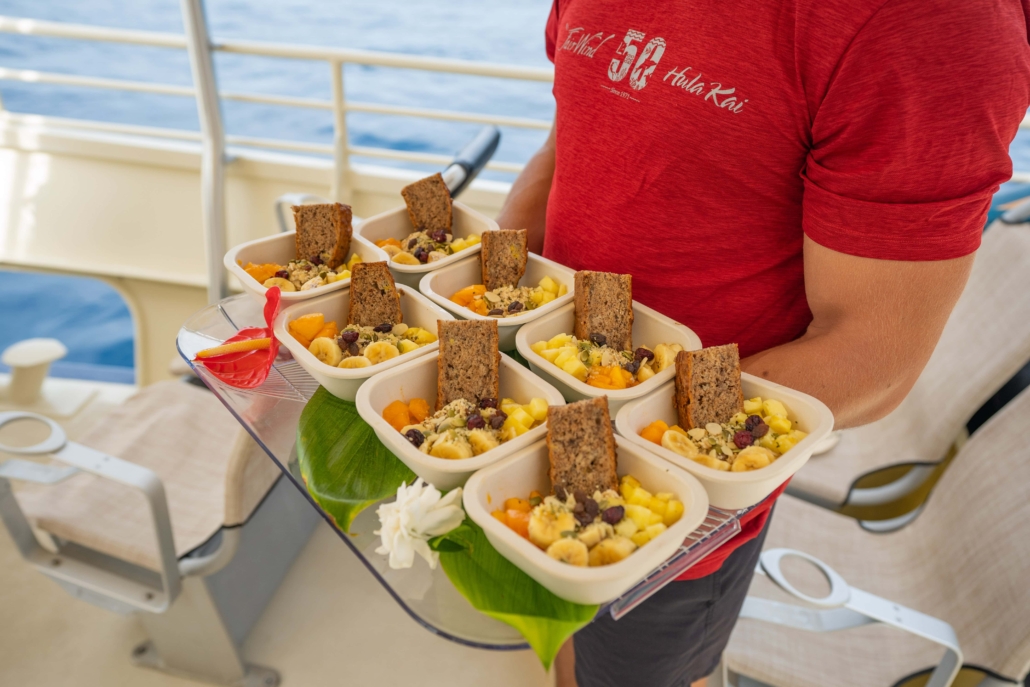 A crew member aboard the Hula Kai carrying a tray of breakfast items.